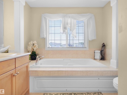 Built-in soaking tub with tile surround, wood cabinetry, and fluted column architectural details - 614 Silver Berry Road Nw, Edmonton, AB - Indoor Photo Showing Bathroom
