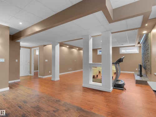Expansive finished lower level featuring wood-finish flooring, recessed lighting, drop ceiling, and a stone-look accent wall - 614 Silver Berry Road Nw, Edmonton, AB - Indoor
