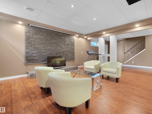 Wood-finish flooring, accent stone wall, recessed lighting, drop ceiling, and a staircase with an iron railing - 614 Silver Berry Road Nw, Edmonton, AB - Indoor