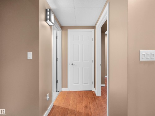Hallway with wood-finish flooring, neutral wall paint, and white paneled doors - 614 Silver Berry Road Nw, Edmonton, AB - Indoor Photo Showing Other Room