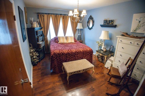 Wood-finish flooring, light blue wall paint, multiple windows with curtains, and a chandelier with four lights - 11739 129 Street Nw, Edmonton, AB 