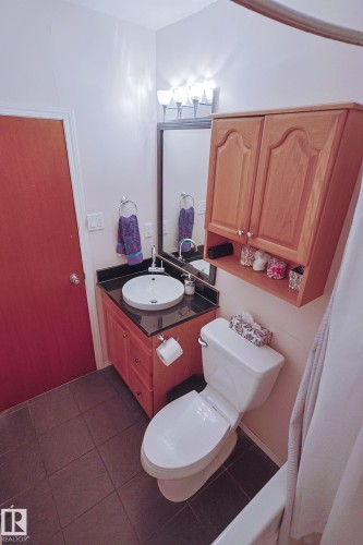 Recessed vanity with a vessel sink, dark countertop, and wood-finish cabinetry - 11739 129 Street Nw, Edmonton, AB 