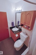 Recessed vanity with a vessel sink, dark countertop, and wood-finish cabinetry - 
