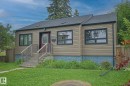 Tan horizontal siding exterior with dark trim windows, dark shingle roof, and a red front entry door - 11739 129 Street Nw, Edmonton, AB 