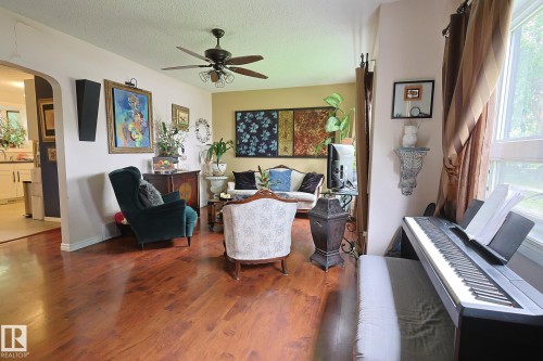 Living area featuring wood-finish flooring, a ceiling fan, and an arched doorway - 11739 129 Street Nw, Edmonton, AB 