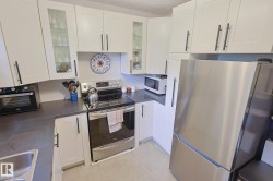White shaker-style cabinetry with matte black hardware, stainless steel appliances, dark countertops, and light-toned flooring - 