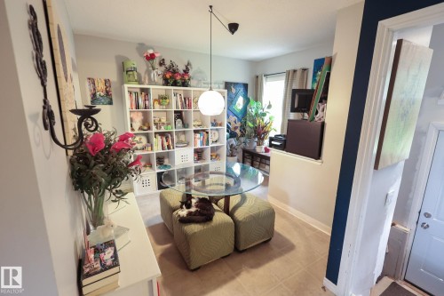 Room featuring tile flooring, built-in shelving, a glass-top table, and a partial wall opening to another space - 11739 129 Street Nw, Edmonton, AB 