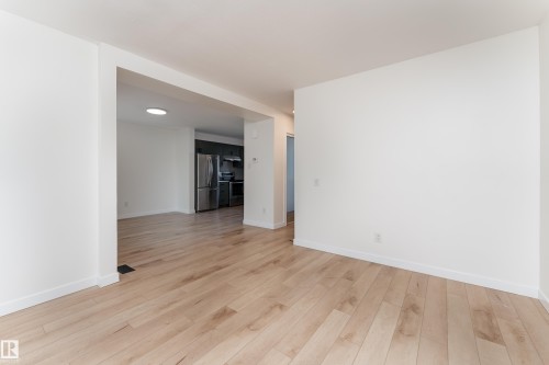 Open-concept living area featuring light wood-finish flooring, white baseboards, and a neutral color palette - #10 1415 62 St Nw, Edmonton, AB - Indoor Photo Showing Other Room