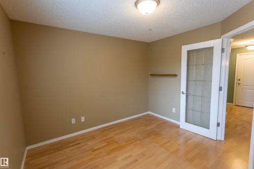 Wood-finish flooring, neutral wall paint, and a textured ceiling - #204 2420 108 St Nw, Edmonton, AB - Indoor Photo Showing Other Room