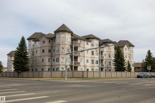 Multi-story building featuring turret-style architectural elements, private balconies, and a perimeter fence - #204 2420 108 St Nw, Edmonton, AB - Outdoor With Facade