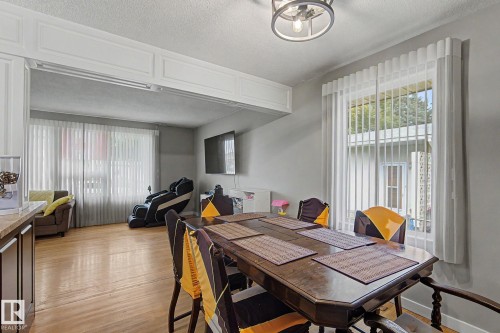 Wood-finish flooring throughout, featuring a dining area with a built-in countertop, and an open concept room with large windows - 4323 114B Street Nw, Edmonton, AB - Indoor Photo Showing Dining Room