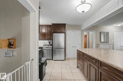 Kitchen featuring stainless steel appliances, dark wood cabinetry, a tiled backsplash, and a large central island with a light-colored countertop - 