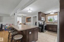 Kitchen featuring dark wood-finish cabinetry, stainless steel appliances, tile backsplash, and an island with countertop seating - 
