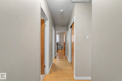 Wood-finish flooring extending throughout, neutral wall paint, and white trim accents - 4323 114B Street Nw, Edmonton, AB - Indoor Photo Showing Other Room