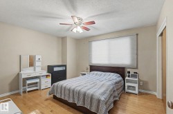 Wood-finish flooring, ceiling fan, window with privacy blinds, and light-toned walls - 
