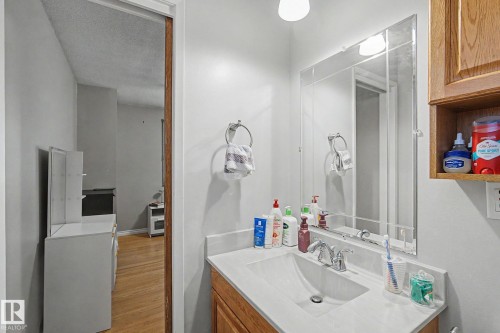 Vanity with integrated sink, chrome faucet, and framed mirror - 4323 114B Street Nw, Edmonton, AB - Indoor Photo Showing Bathroom