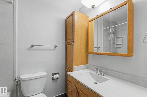 Vanity with an integrated sink, polished chrome faucet, and wood-finish cabinetry - 4323 114B Street Nw, Edmonton, AB - Indoor Photo Showing Bathroom