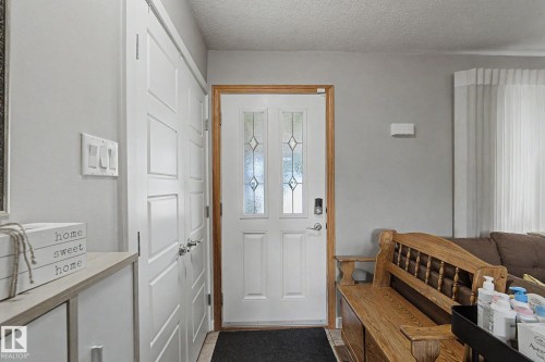 Entry door with decorative glass inserts and wood trim - 4323 114B Street Nw, Edmonton, AB - Indoor Photo Showing Other Room