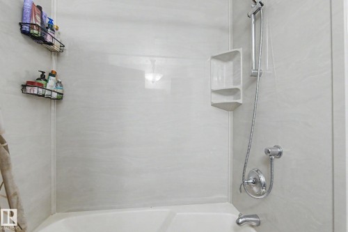 Bathtub with light-colored wall panels and a showerhead on a flexible hose - 4323 114B Street Nw, Edmonton, AB - Indoor Photo Showing Bathroom