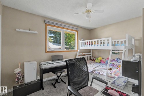 Neutral wall color, window with wood-finish trim, ceiling fan with integrated lighting, carpeted flooring - 4323 114B Street Nw, Edmonton, AB - Indoor Photo Showing Office