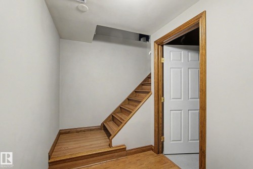Wood-finish flooring with matching staircase treads and risers - 4323 114B Street Nw, Edmonton, AB - Indoor Photo Showing Other Room