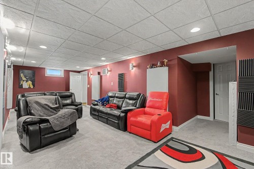 Finished Basement Recreation Room featuring vibrant red accent walls, recessed ceiling lighting, neutral tile flooring, and built-in white cabinetry - 4323 114B Street Nw, Edmonton, AB - Indoor