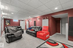 Finished Basement Recreation Room featuring vibrant red accent walls, recessed ceiling lighting, neutral tile flooring, and built-in white cabinetry - 