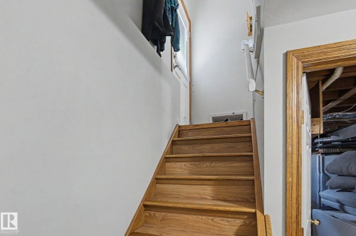 Wood-finish staircase with solid risers, solid wood door frame, and white painted walls - 4323 114B Street Nw, Edmonton, AB - Indoor Photo Showing Other Room