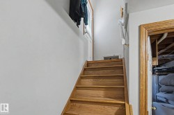 Wood-finish staircase with solid risers, solid wood door frame, and white painted walls - 