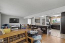 Open-concept living area featuring wood-finish flooring, a kitchen island with seating, dark wood cabinetry, a tiled kitchen floor, and a window with natural light - 4323 114B Street Nw, Edmonton, AB  - Indoor 