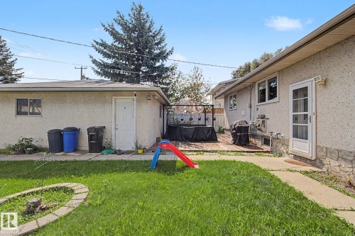 Expansive backyard featuring a lush lawn, concrete pathway, and a wood-finish deck - 4323 114B Street Nw, Edmonton, AB - Outdoor
