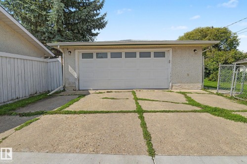 Detached garage featuring a white overhead door with upper window panels and a textured stucco exterior - 4323 114B Street Nw, Edmonton, AB - Outdoor