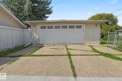Detached garage featuring a white overhead door with upper window panels and a textured stucco exterior - 