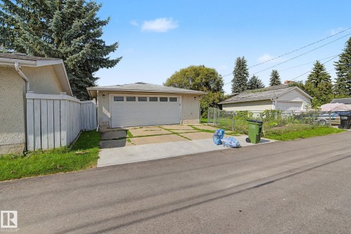 Detached garage with a paneled door, concrete driveway, and a white privacy fence - 4323 114B Street Nw, Edmonton, AB - Outdoor