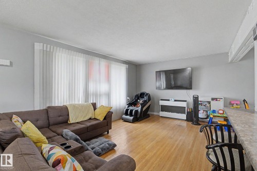 Wood-finish flooring throughout, light gray wall paint, and white window treatments - 4323 114B Street Nw, Edmonton, AB - Indoor Photo Showing Living Room