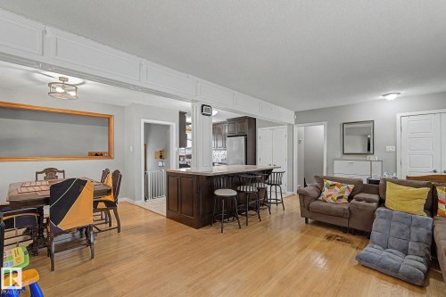 Hardwood flooring throughout, a kitchen island with seating, dark wood cabinetry, and recessed lighting - 4323 114B Street Nw, Edmonton, AB - Indoor Photo Showing Living Room