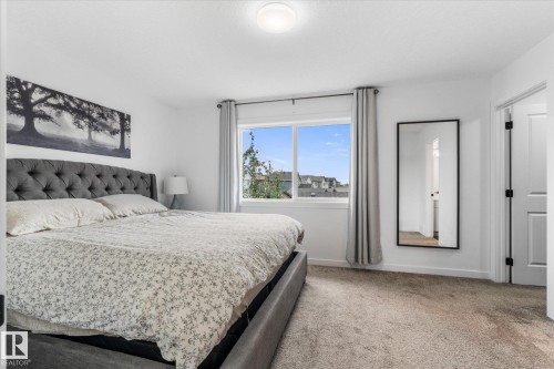 Neutral wall paint, window with exterior scenery, overhead flush mount lighting, paneled doors with dark hardware, and carpet flooring - 9 Dillingham Avenue, Fort Saskatchewan, AB - Indoor Photo Showing Bedroom