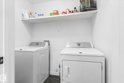 Laundry area with floating shelf, white walls, and dark flooring - 9 Dillingham Avenue, Fort Saskatchewan, AB - Indoor Photo Showing Laundry Room