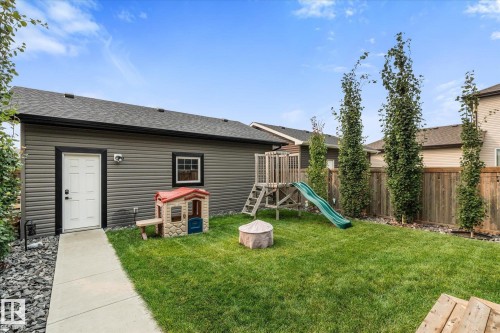 Manicured lawn with a privacy fence, concrete walkway, and a detached garage featuring horizontal siding and a shingled roof - 9 Dillingham Avenue, Fort Saskatchewan, AB - Outdoor