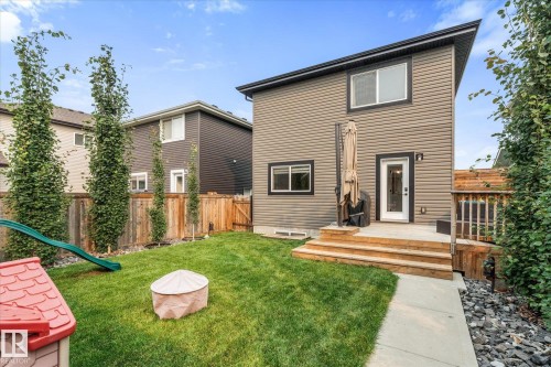 Expansive backyard with a manicured lawn, a wooden fence, and mature trees - 9 Dillingham Avenue, Fort Saskatchewan, AB - Outdoor With Deck Patio Veranda