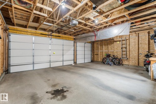 Two overhead garage doors, concrete flooring, exposed wood beam ceiling, and panel walls - 9 Dillingham Avenue, Fort Saskatchewan, AB - Indoor Photo Showing Garage