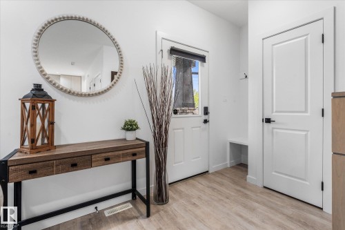 Entryway featuring wood-finish flooring, a white paneled door with matte black hardware, and a built-in bench - 9 Dillingham Avenue, Fort Saskatchewan, AB - Indoor Photo Showing Other Room