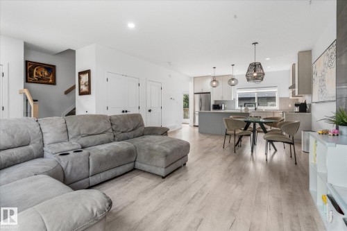 Open-concept main level featuring wood-finish flooring, a kitchen with stainless steel appliances, and an island with bar seating - 9 Dillingham Avenue, Fort Saskatchewan, AB - Indoor Photo Showing Living Room