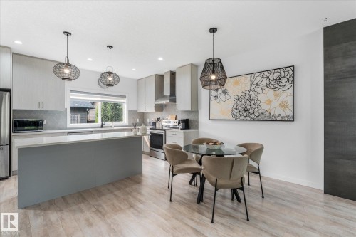 Kitchen featuring light wood-finish flooring, a central island with a light-colored countertop, stainless steel appliances, and pendant lighting - 9 Dillingham Avenue, Fort Saskatchewan, AB - Indoor