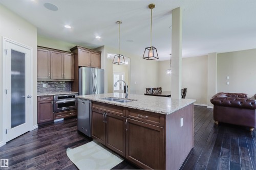 Kitchen featuring a central island with an undermount sink, stainless steel appliances, dark wood-finish flooring, and pendant lighting - 864 Armitage Wynd Sw, Edmonton, AB - Indoor Photo Showing Kitchen With Double Sink With Upgraded Kitchen