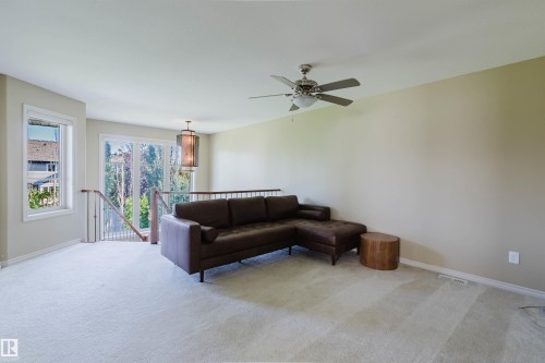 Spacious carpeted area with abundant natural light, featuring a ceiling fan and a modern decorative pendant light - 864 Armitage Wynd Sw, Edmonton, AB - Indoor Photo Showing Other Room