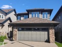 Contemporary home with a shingle roof, stone accent columns, a two-car garage, and multiple upper-level windows - 864 Armitage Wynd Sw, Edmonton, AB  - Outdoor 
