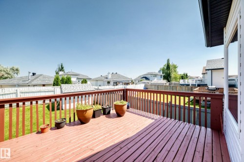 Expansive outdoor deck with wood railing, offering a clear view of the surrounding properties, alongside a well-maintained lawn and a detached shed - 16227 64 Street Nw, Edmonton, AB - Outdoor With Deck Patio Veranda With Exterior