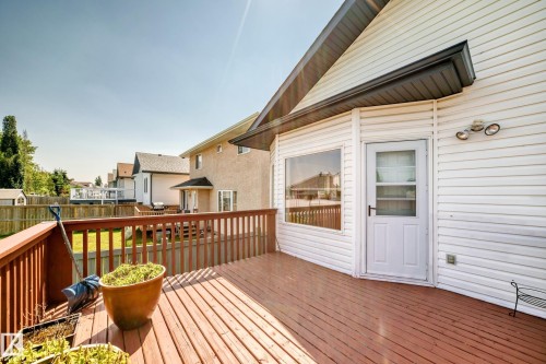 Spacious wooden deck with a finished railing, white exterior siding, and a glass-paned door - 16227 64 Street Nw, Edmonton, AB - Outdoor With Deck Patio Veranda With Exterior