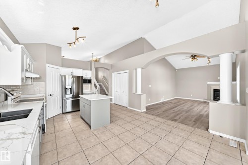 Expansive kitchen featuring tile flooring, white cabinetry, a center island, stainless steel appliances, and quartz countertops - 16227 64 Street Nw, Edmonton, AB - Indoor Photo Showing Kitchen With Double Sink